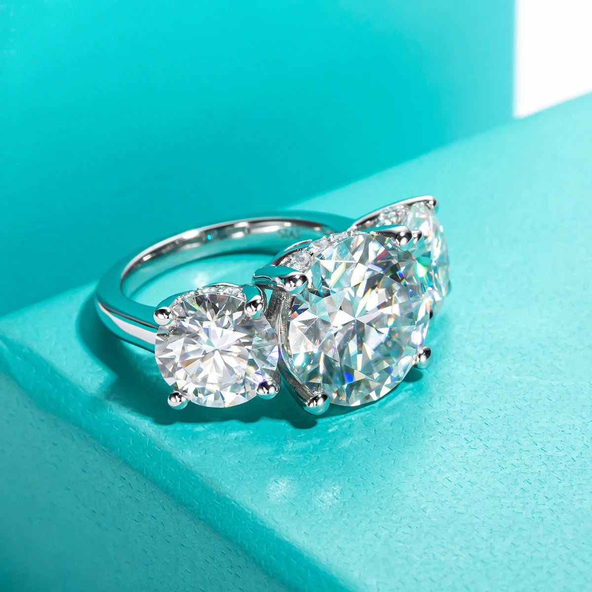 A solid silver platinum plated engagement ring with three round moissanite stones set on top, eleven carats